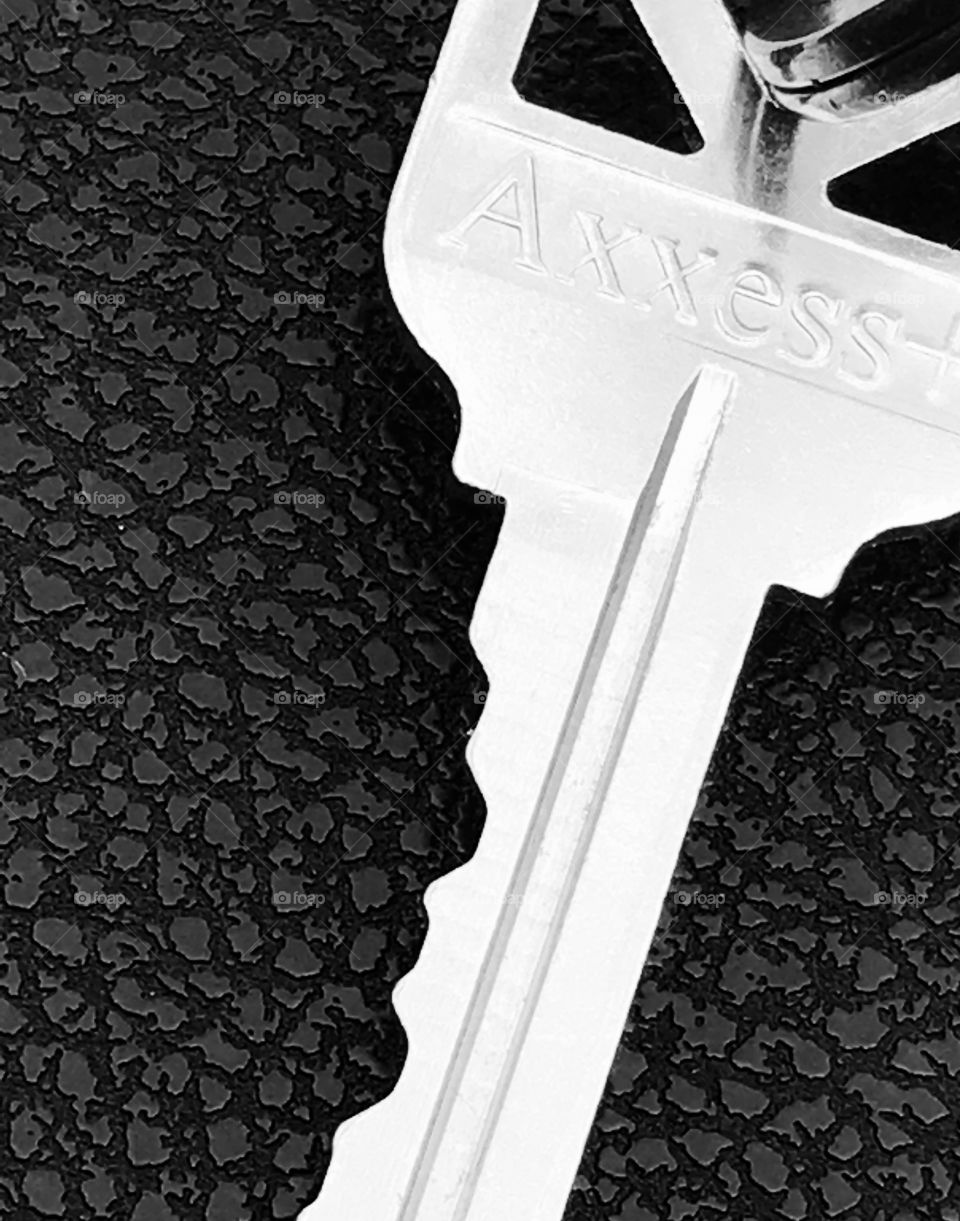 Silver key on black textured background 