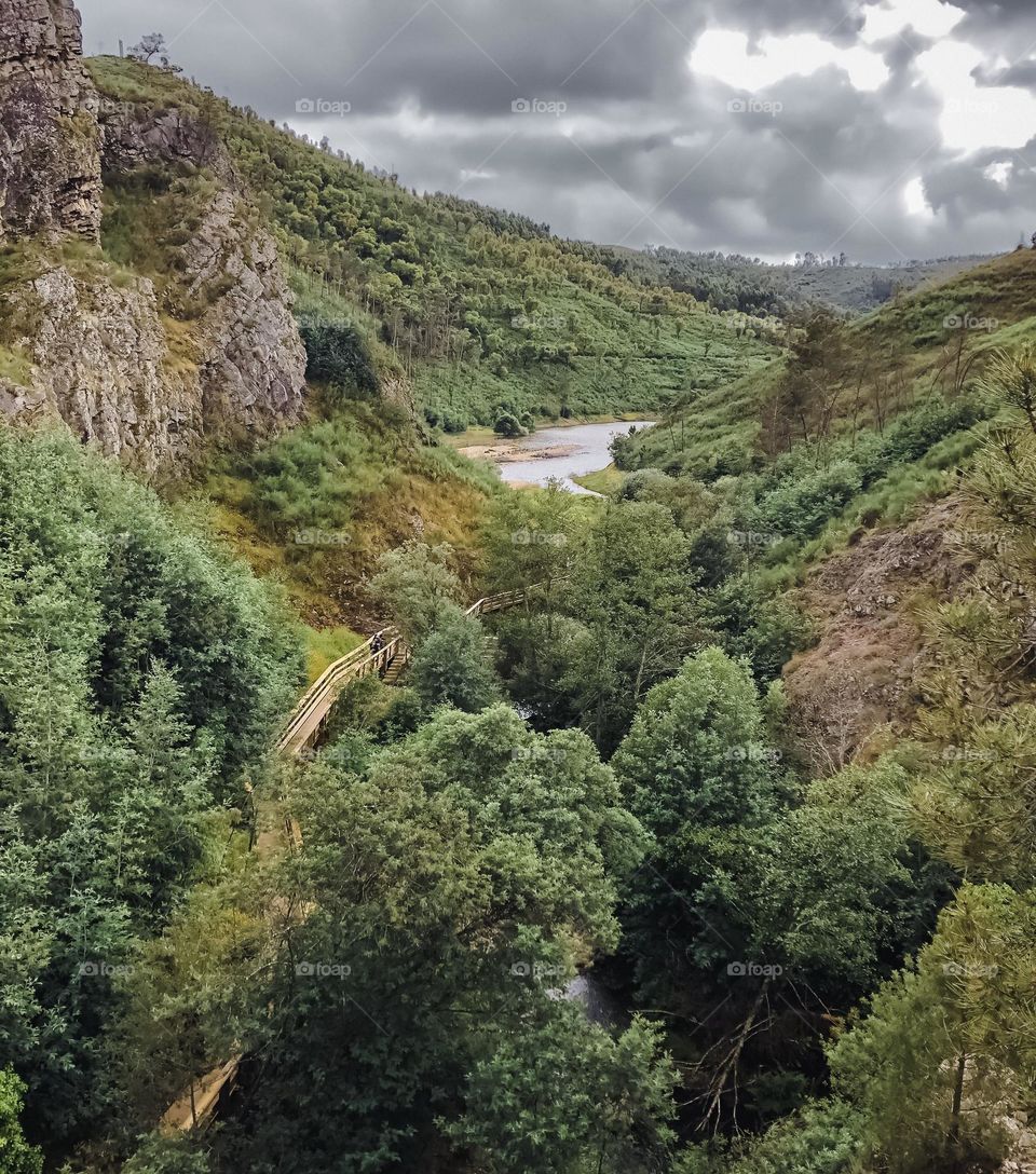 A wooden trail follows the river through the valley at Penedo Furado, Portugal 