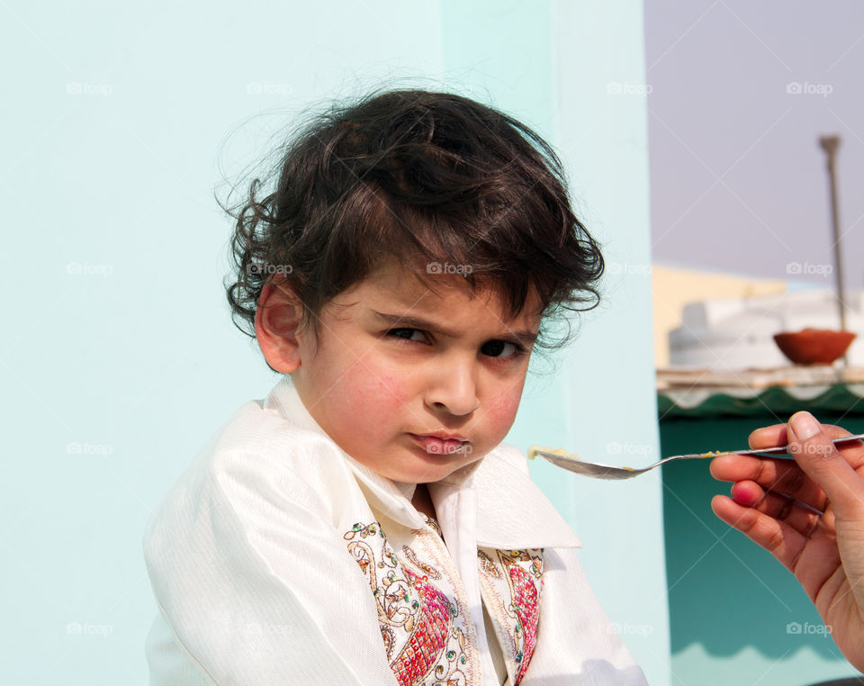 Cute Indian baby boy with expression while eating food outdoors