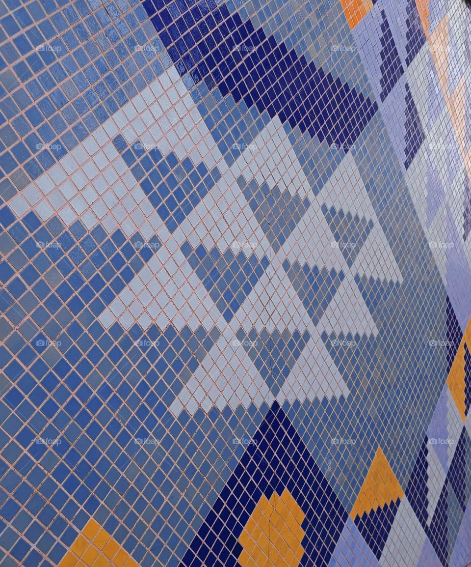 Close up of a geometrical mosaic with blue, white and orange triangles