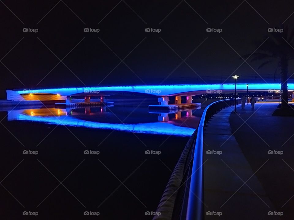 blue illuminated bridge , reflection on the water at night