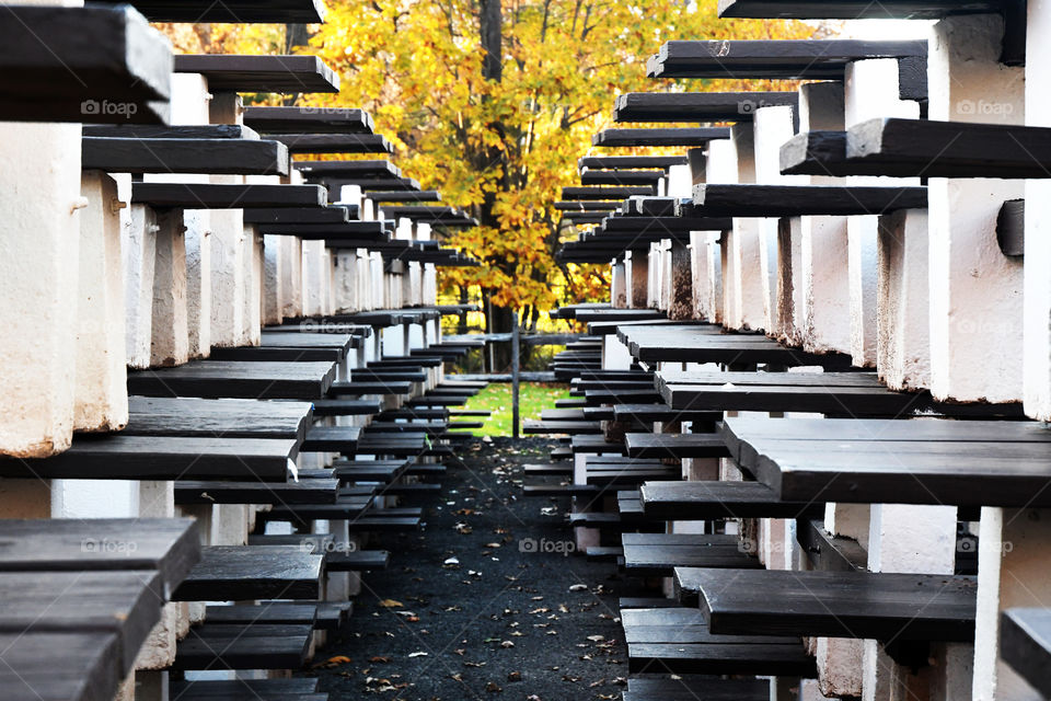 Stacked up park picnic tables put away for the change of season give way to beautiful fall foliage.