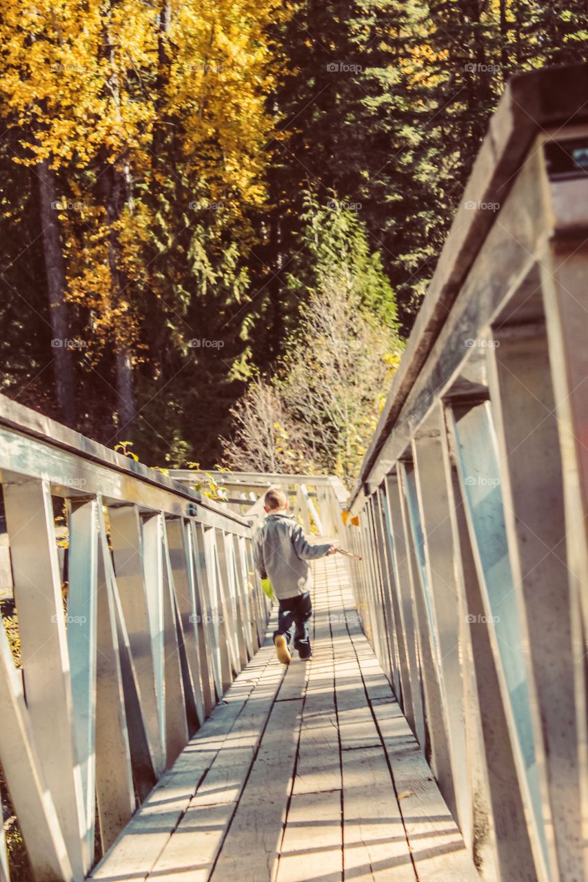 Boy running on mountain trail bridge in the autumn 