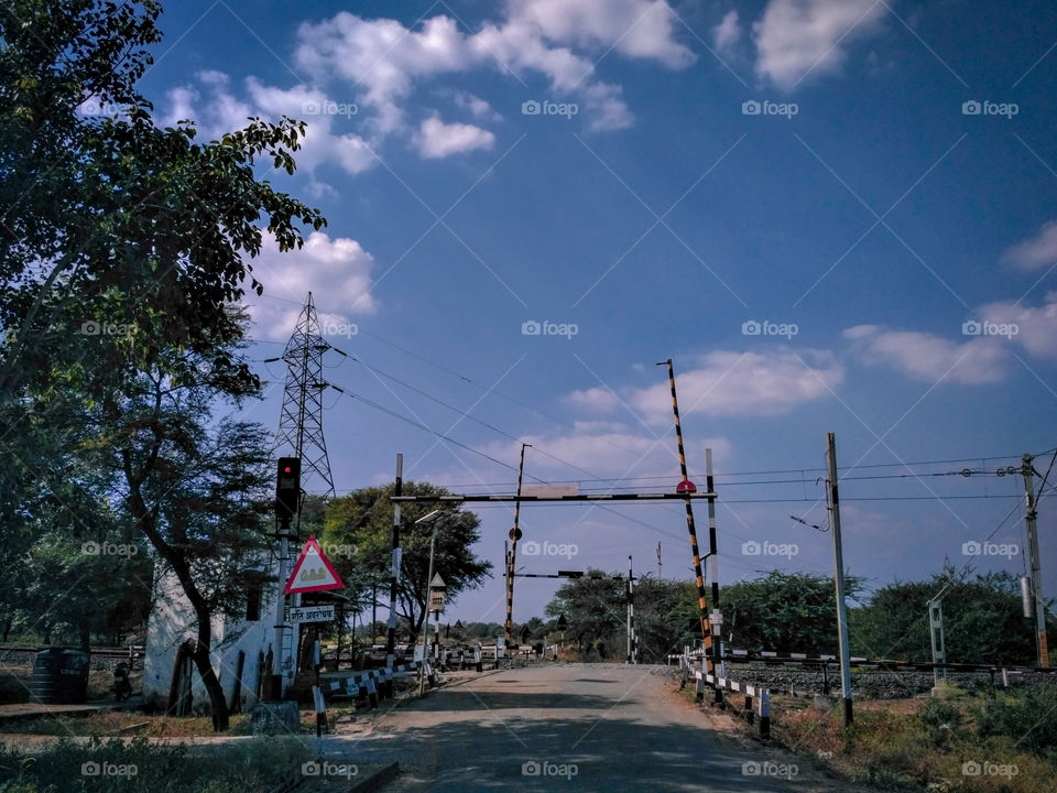 Railway Level Crossing Gates / Transmission Pole / RailRoad / Cloudy sky / Randomly clicked