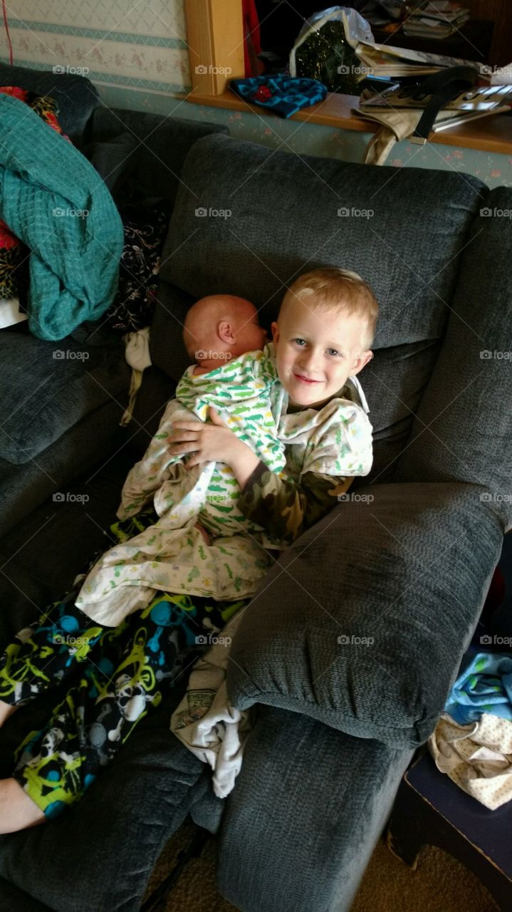 Boy holding infant brother for first time.