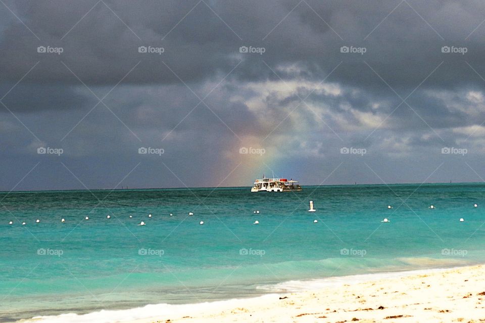 A rainbow appears in front of a boat in the Turks & Caicos Islands