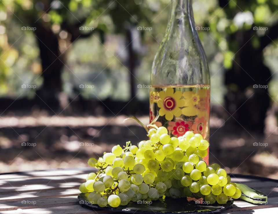 Homegrown grapes with a bottle of homemade wine on a wooden table in a garden