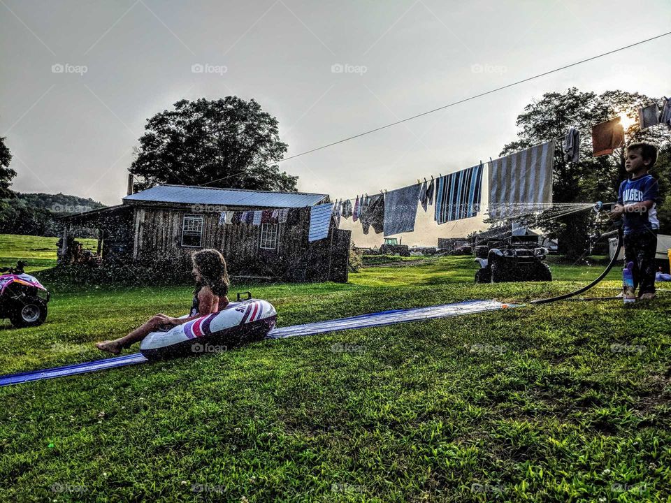 Boy hosing down waterslide for girl