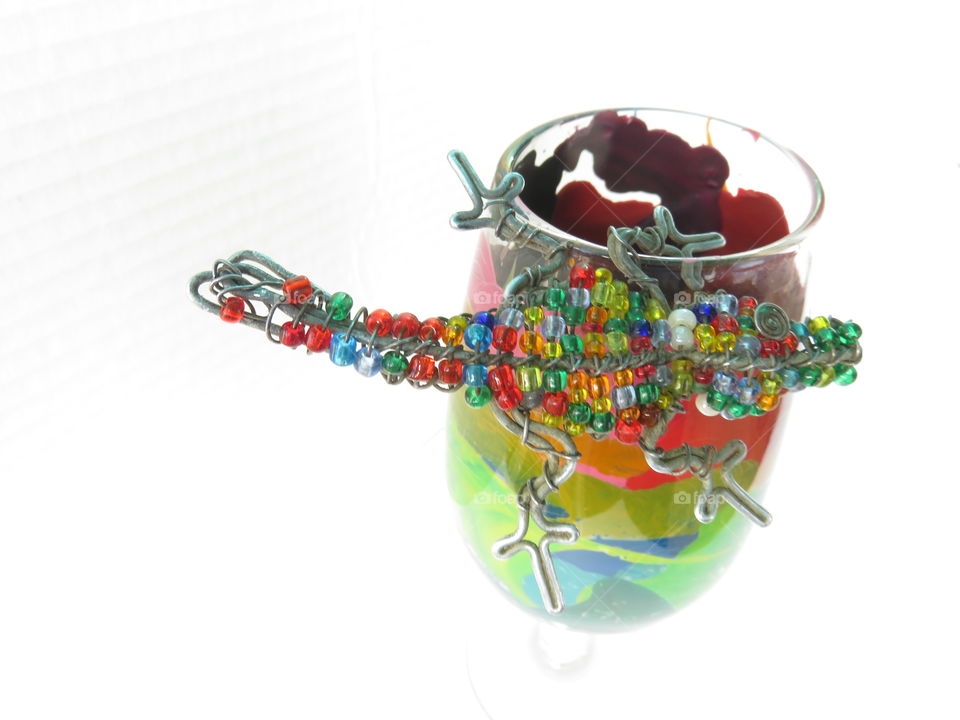 Glass with melted crayons and beads lizard with white background