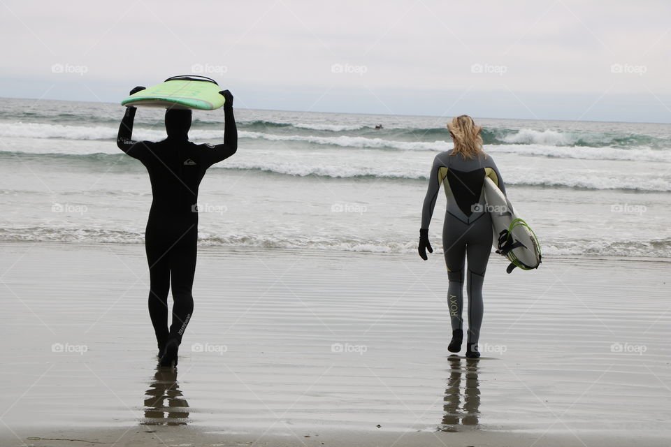Surfers  carrying their boards , the ocean waves are waiting for a ride