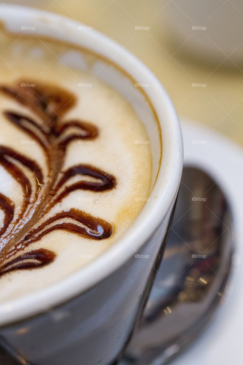 Cappuccino . A close up shot of a coffee with pattern and spoon