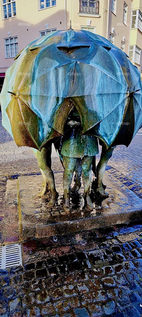 This beautiful modern art metal sculpture of a group of pedestrians covering themselves with their umbrellas to stay dry during the rain was found in „Trelleborg“, „Sweden“ by the „Baltic Sea“. 2023. Hypnotic Productions