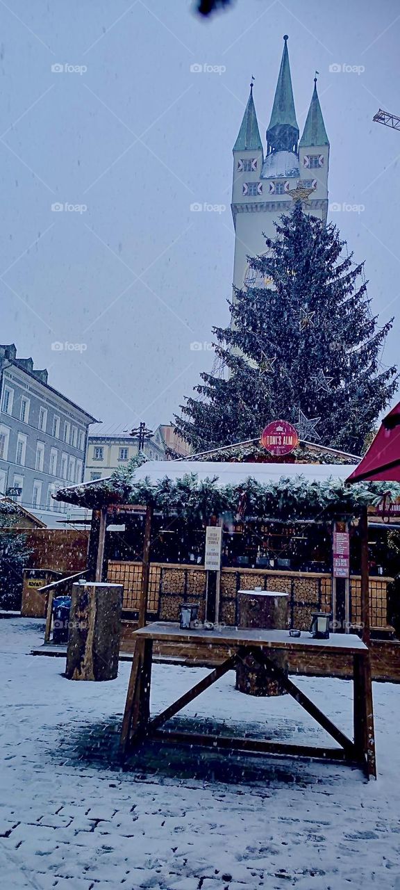The „Christkindlmarkt“, a market with all things Christmas is open at this time every year in a small town in „Bavaria“, Germany. On the top right you see the medieval city clock tower with five minaret rooftops. 2022. Hypnotic Productions