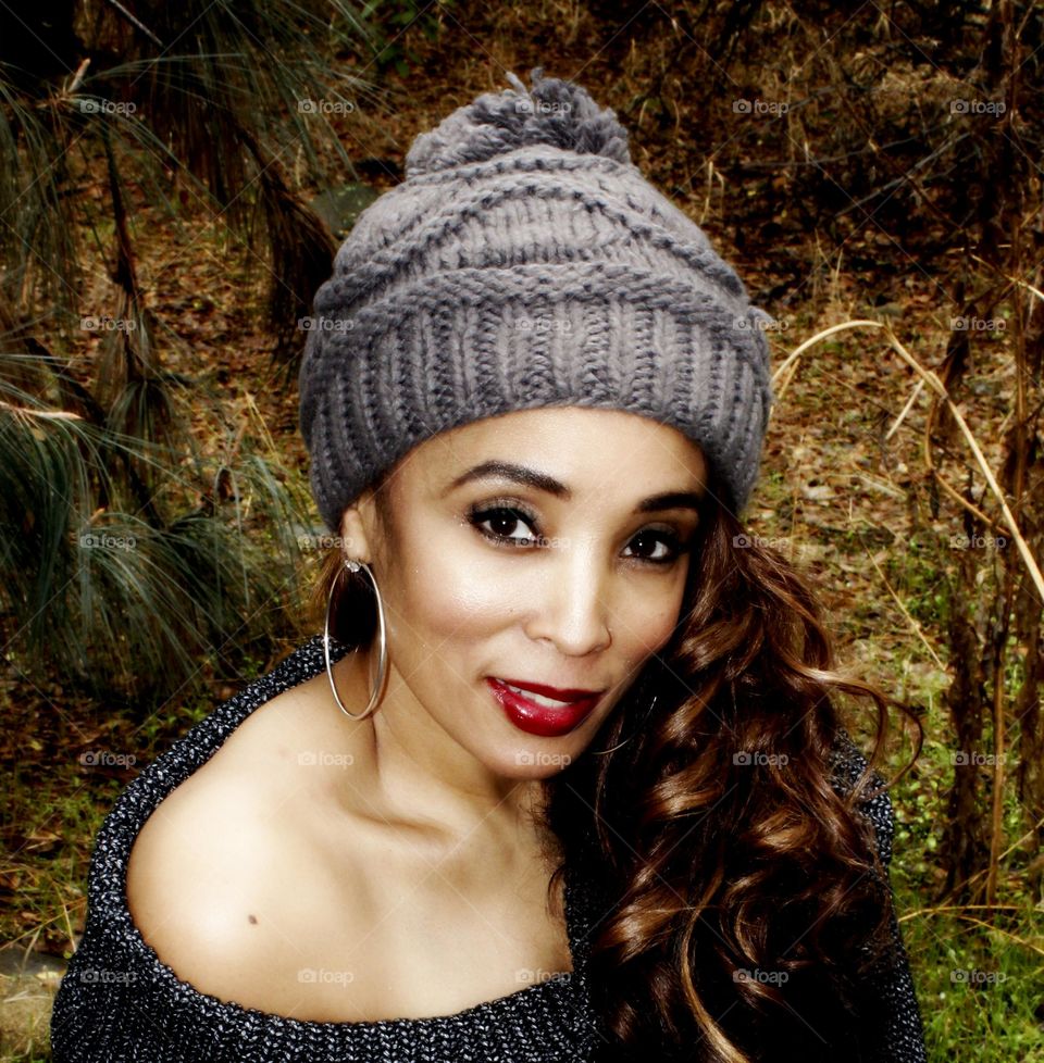 beautiful woman sitting on a rock in nature looking at camera