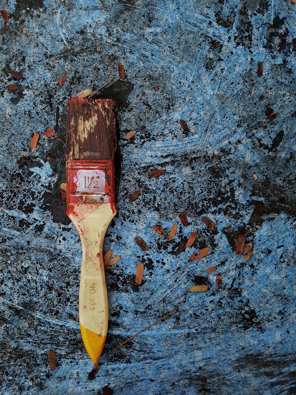 brush with dry red paint on a dirty blu