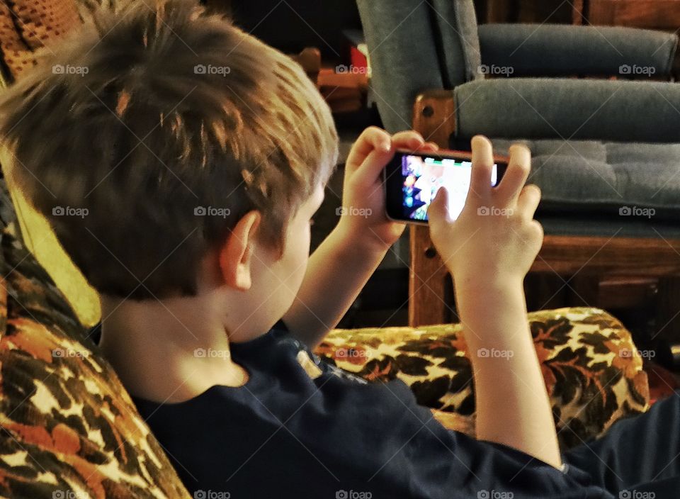 Young Boy Playing On A Smartphone
