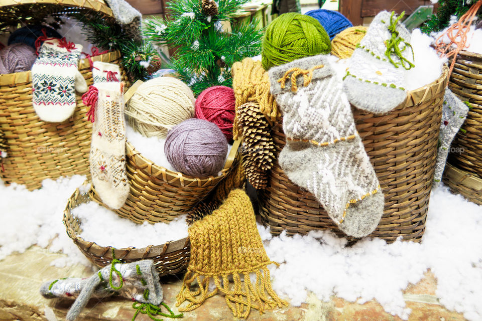 basket with balls of wool yarn and knitted socks and mittens