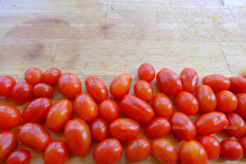 Red grape cherry tomatoes on chooping board.