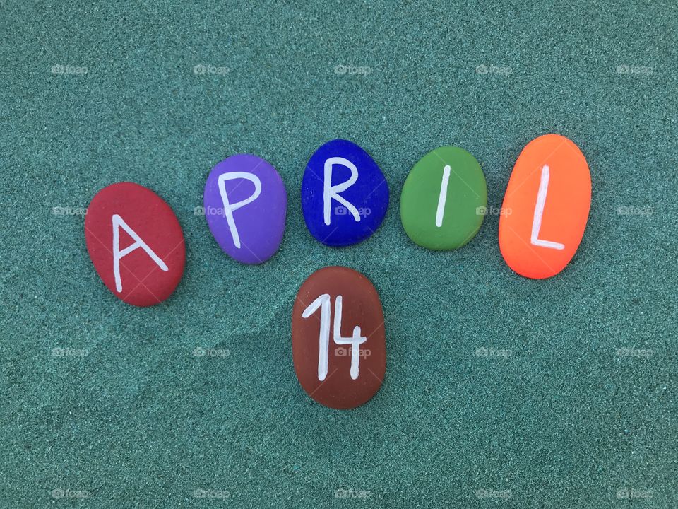 14 April, calendar date on colored stones over green sand 