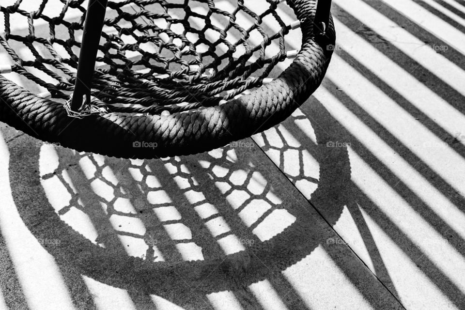 Rope braided swing with diagonal shadows on the floor