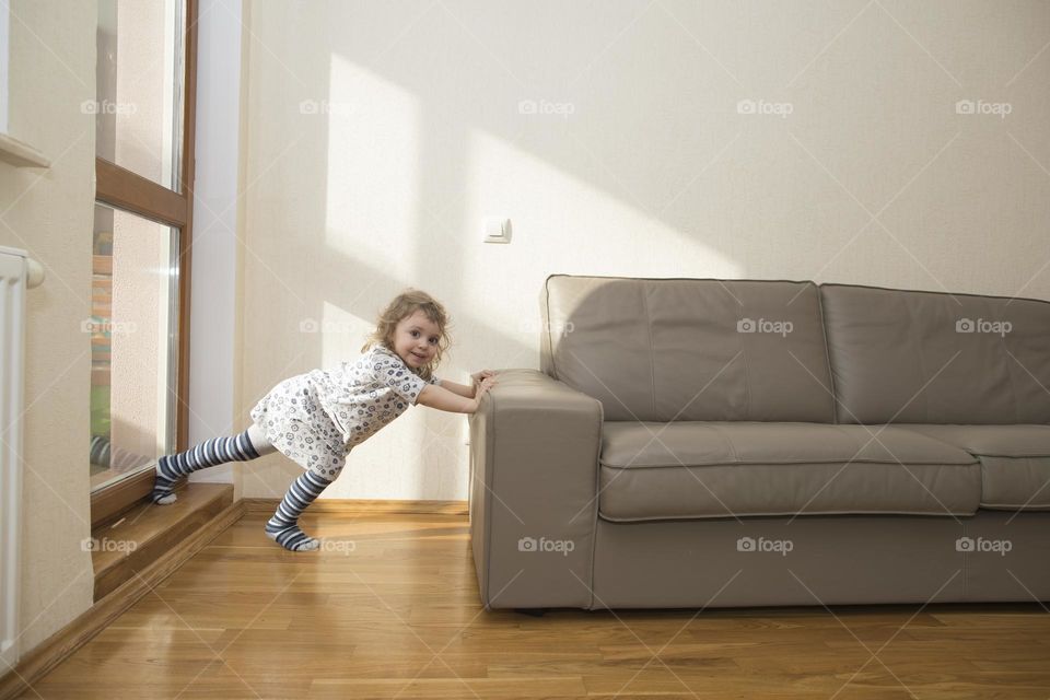 Girl of 3 years is happy to move the sofa