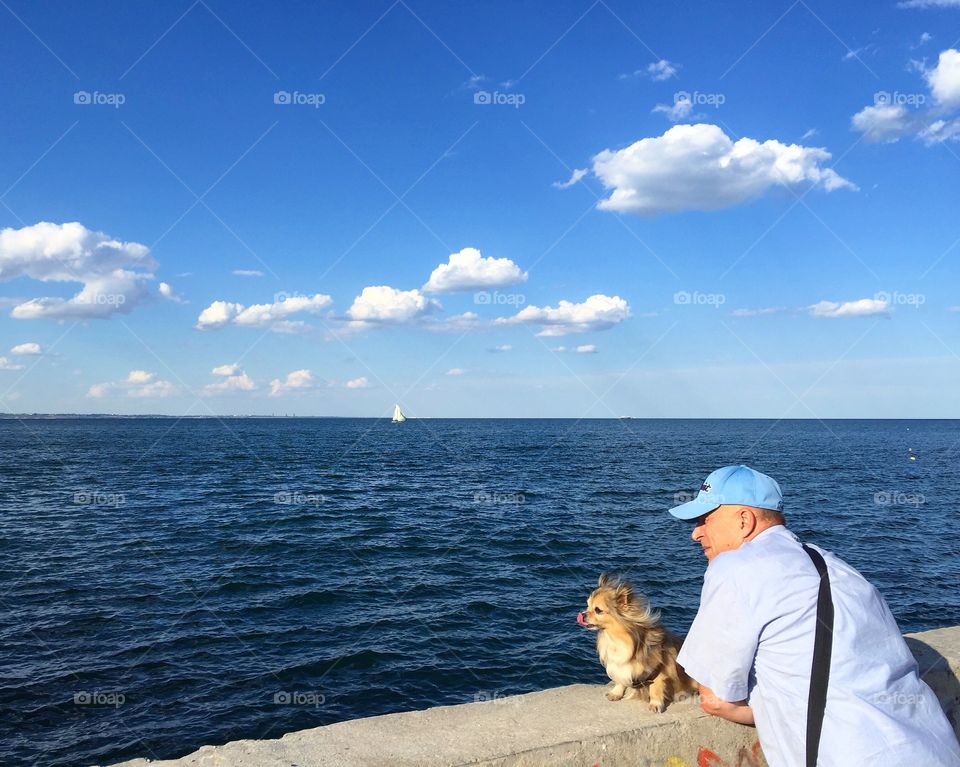 The man and the dog, blue sea and white clouds 