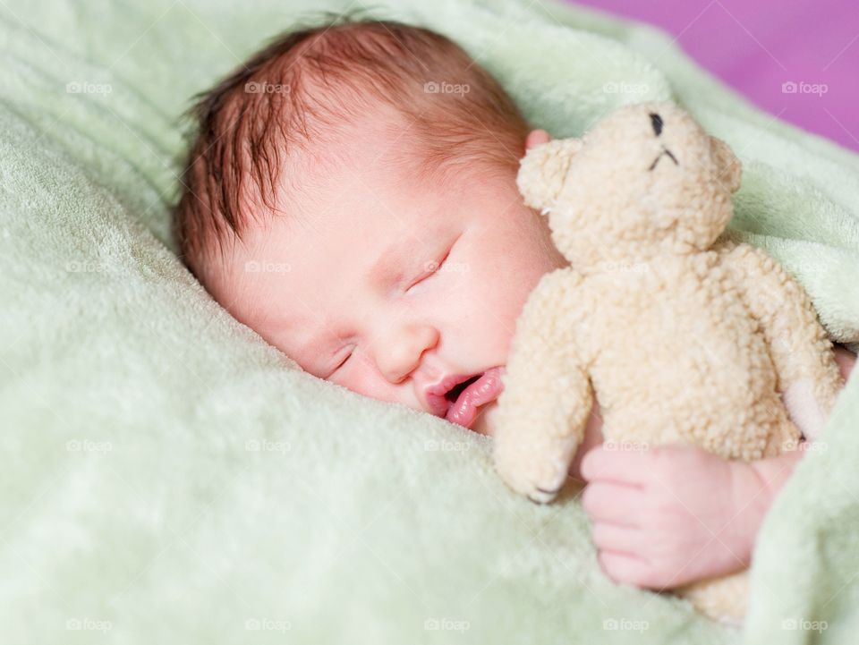 Small baby sleeping on bed with toy