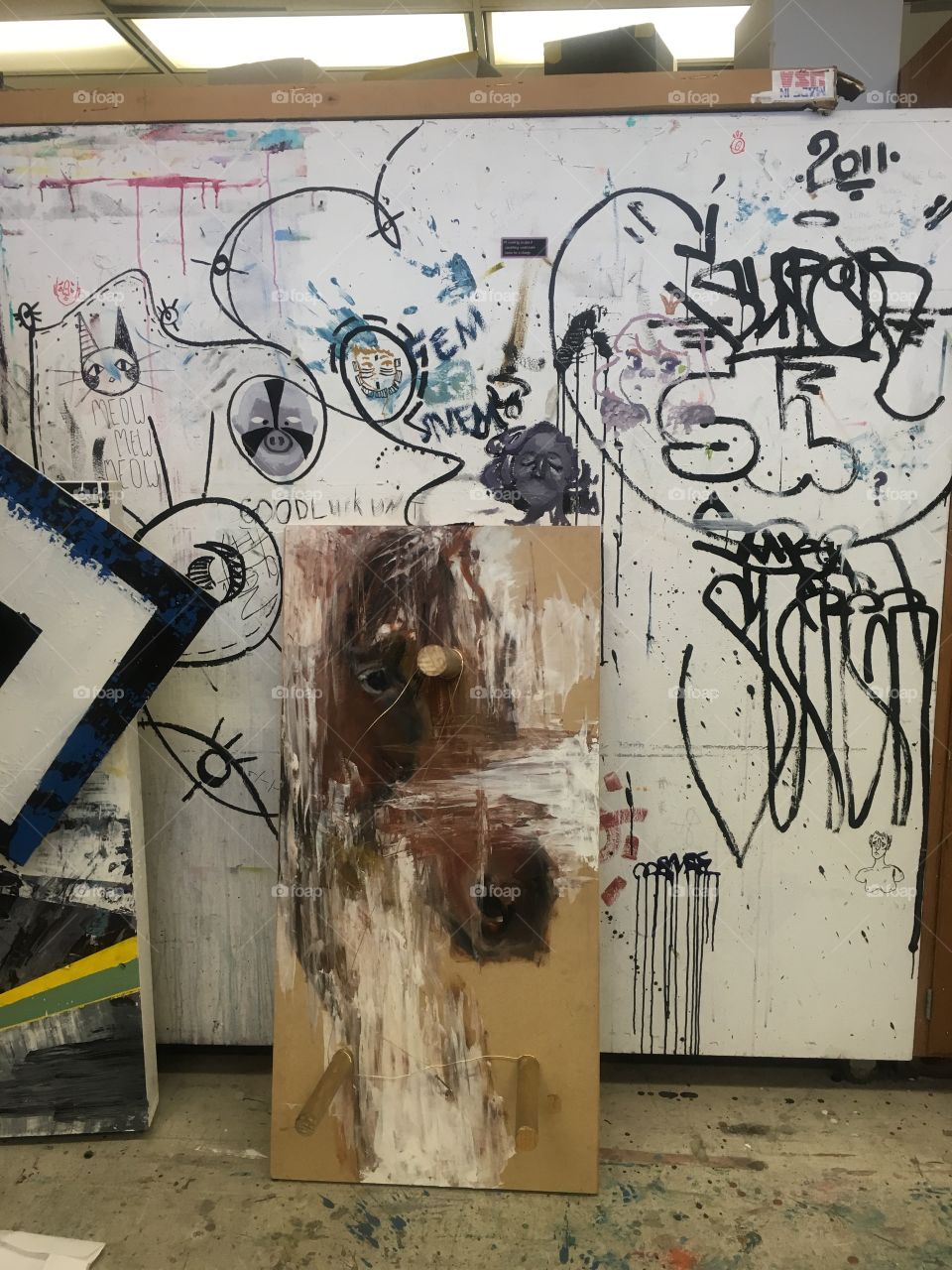 A worn wooden wall covered in various artistic and stylistic graffiti tags