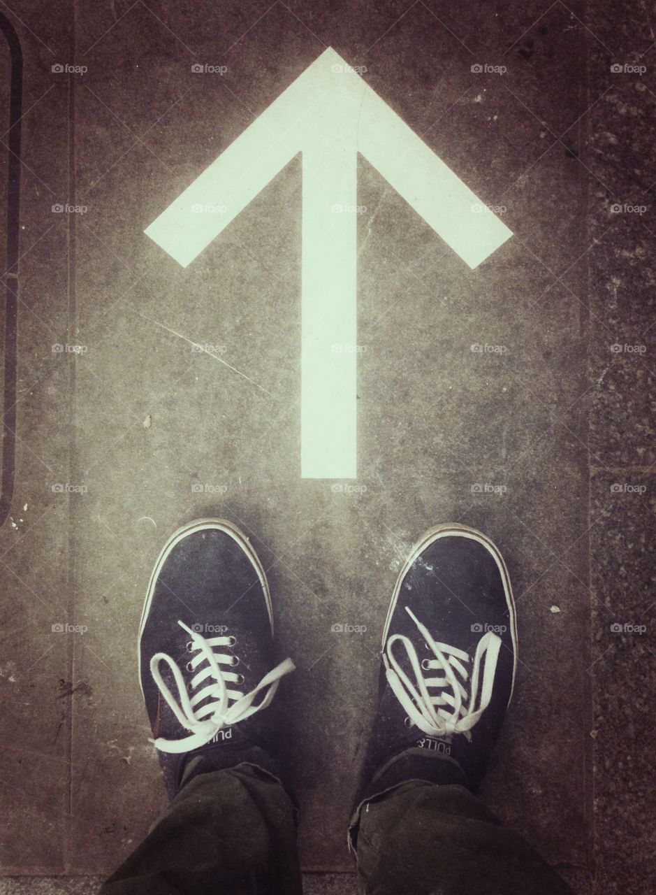 Blue shoes in front of the white arrow on the floor