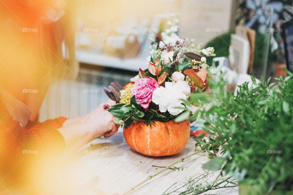 DIY autumn flower arrangement bouquet in pumpkin, florist at work, floristry studio