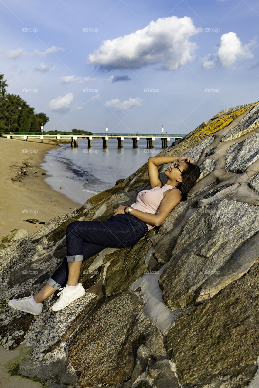 Beautiful lady lying on the rock at the beach