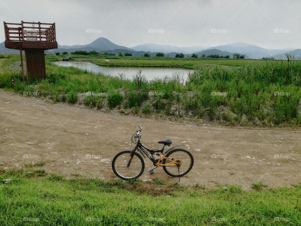 One lonely bicycle on the way to Suncheon Bay wetlands with a lake and a mountain in the lush background.