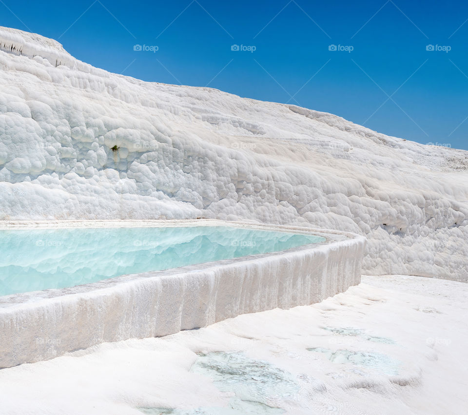 White like snow terrace with turquoise lagoon in the Travertines of Pamukkale. Known as the Cotton Castle. Turkey.