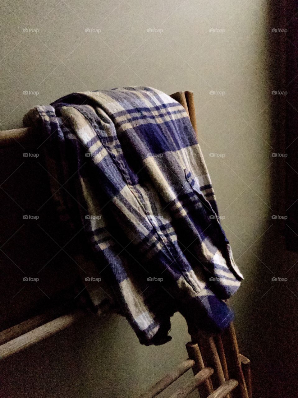 Blue plaid flannel shirt folded over wooden clothes rack 
