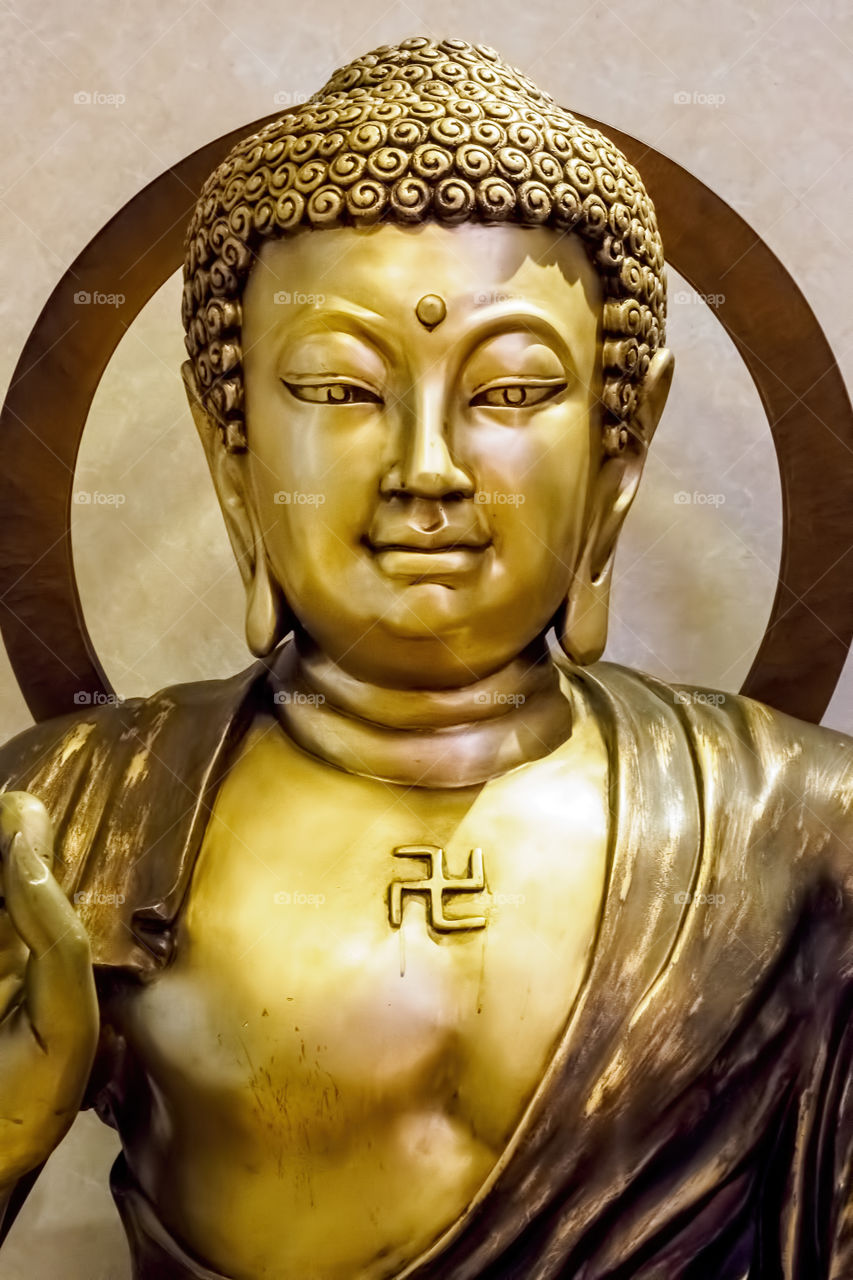 Bronze statue of the Lord Buddha in closeup. It features the iconic serene facial expression. Such a statue is commonly seen in a sitting or meditating posture.