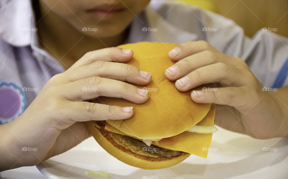 Hamburger fish and cheese in hand asia boy holding the eating.