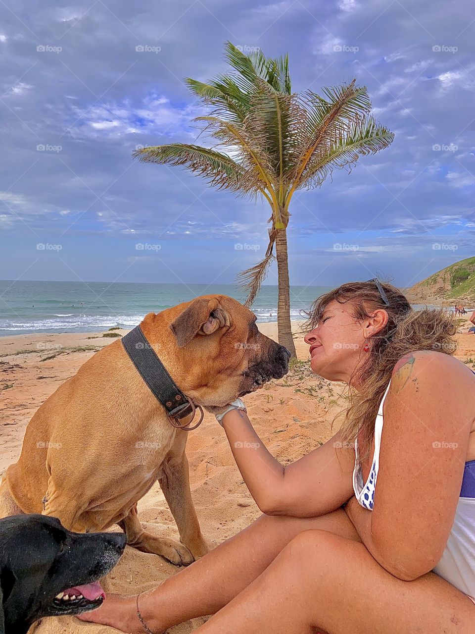 Woman cuddling dog in the beach 