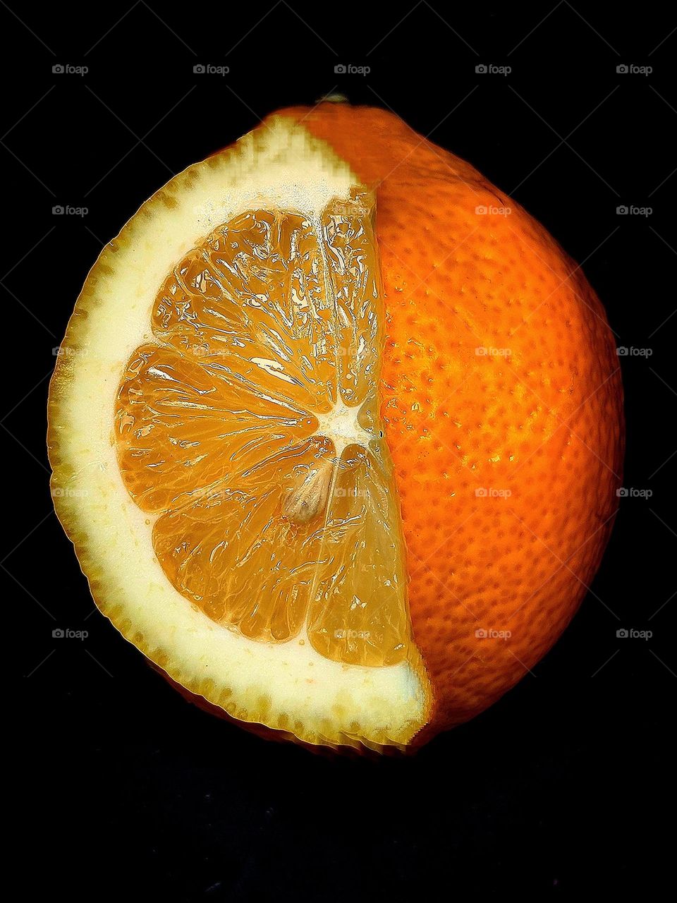 Black background.  Half of a yellow lemon lies on top of an orange round orange.  Color contrast