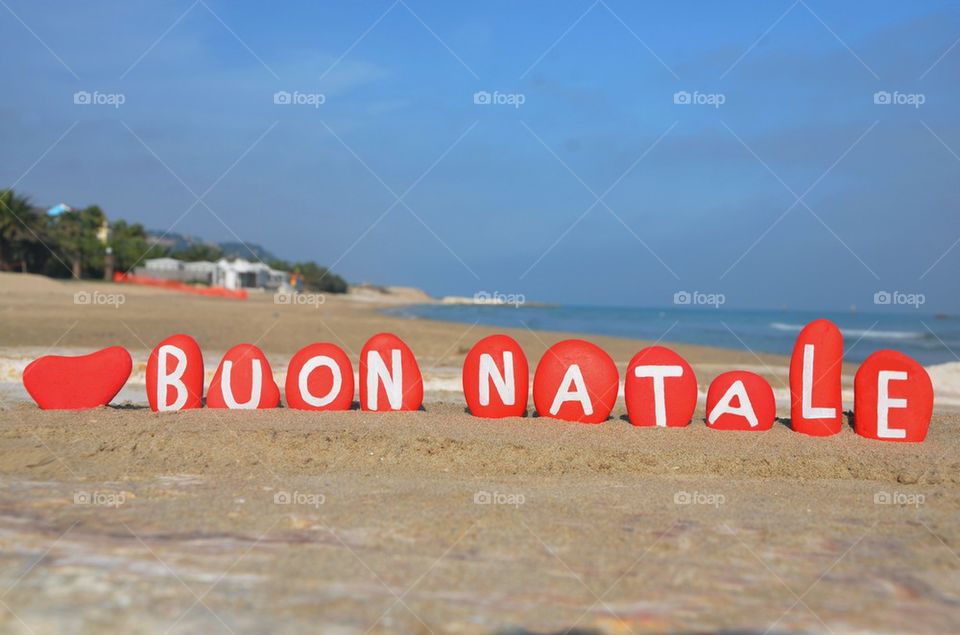 Buon Natale, red stones composition on the sand