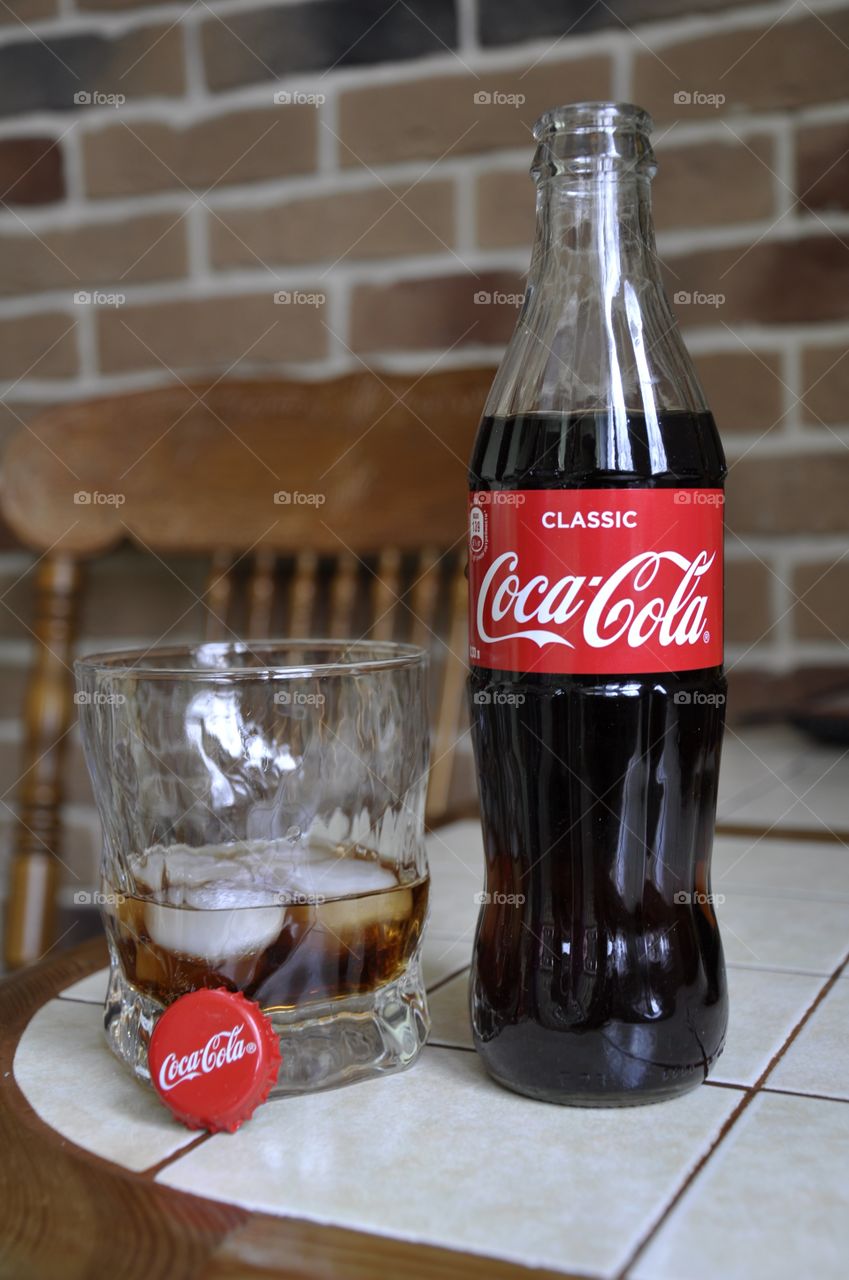 A bottle of Coca - Cola and a glass are on the table