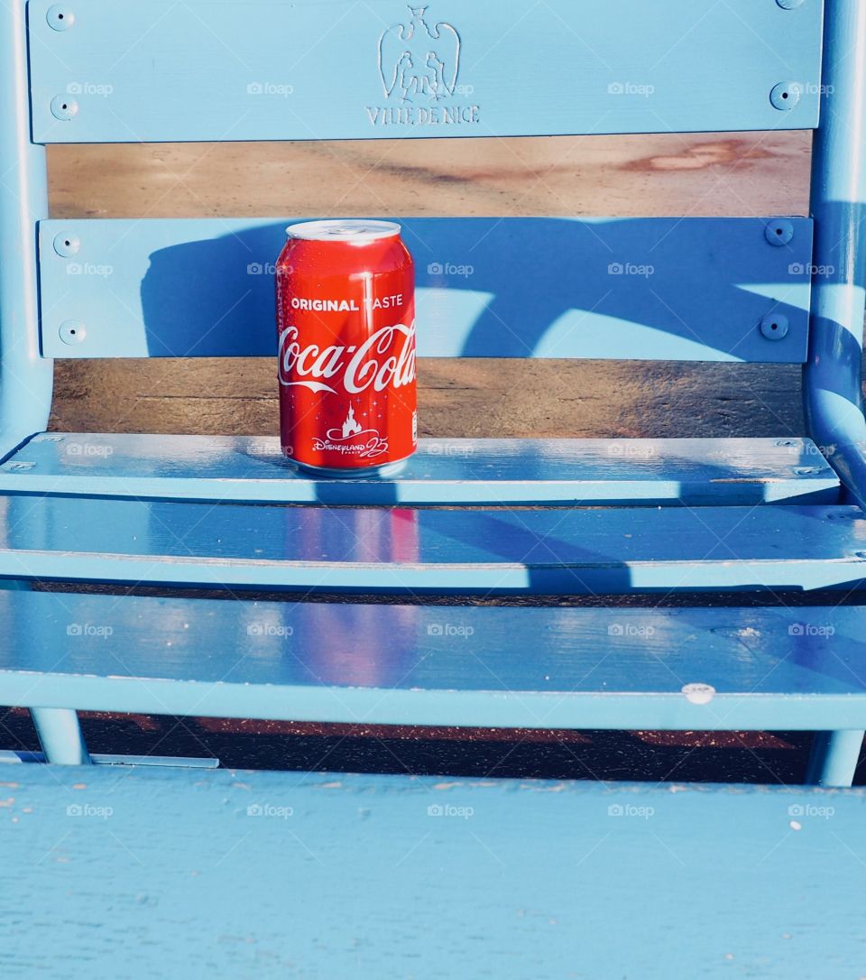 A can of Coca Cola on a blue chair in Nice, France.