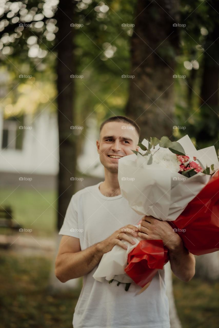 happy young dad is smiling and holding bouquets of flowers given by children for his birthday