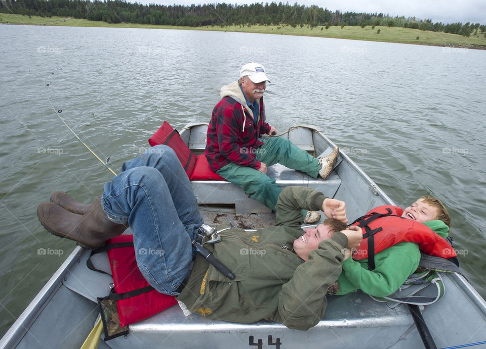 Grandfather drives the boat as his son and grandson play while on a