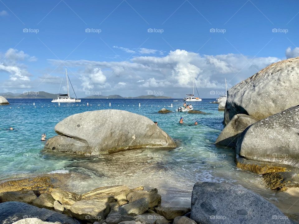 People swimming between large boulders on the beach at The Baths in Virgin Gorda