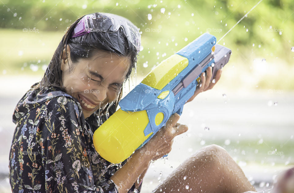 Asian woman holding a water gun play Songkran festival or Thai new year in Thailand.