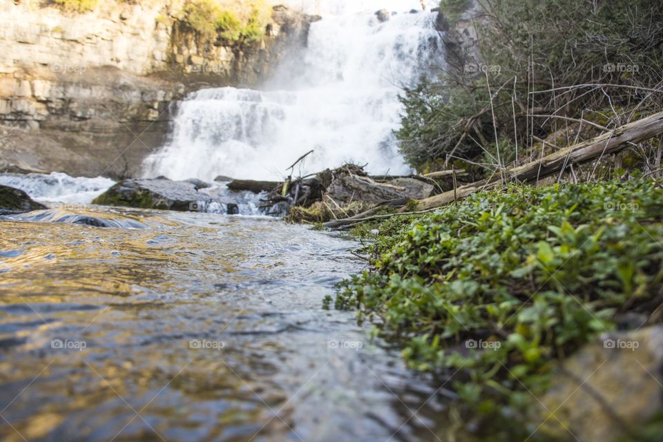 Water rushes into the river as the waterfall moves in the background 