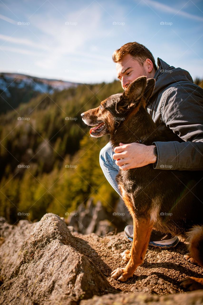 Man on a hike with his dog admiring the view over a cliff