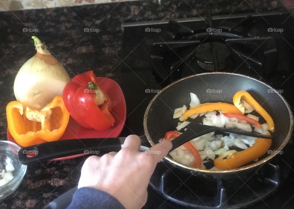 Preparing chopped bell peppers and onions for a sautéed meal 