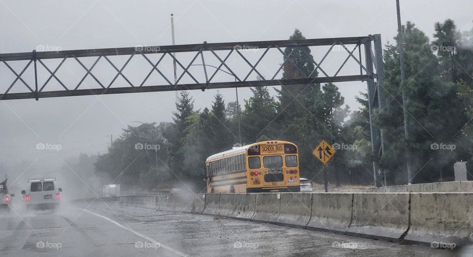 yellow bus driving children to school in commuter traffic on a gray rainy morning in Oregon