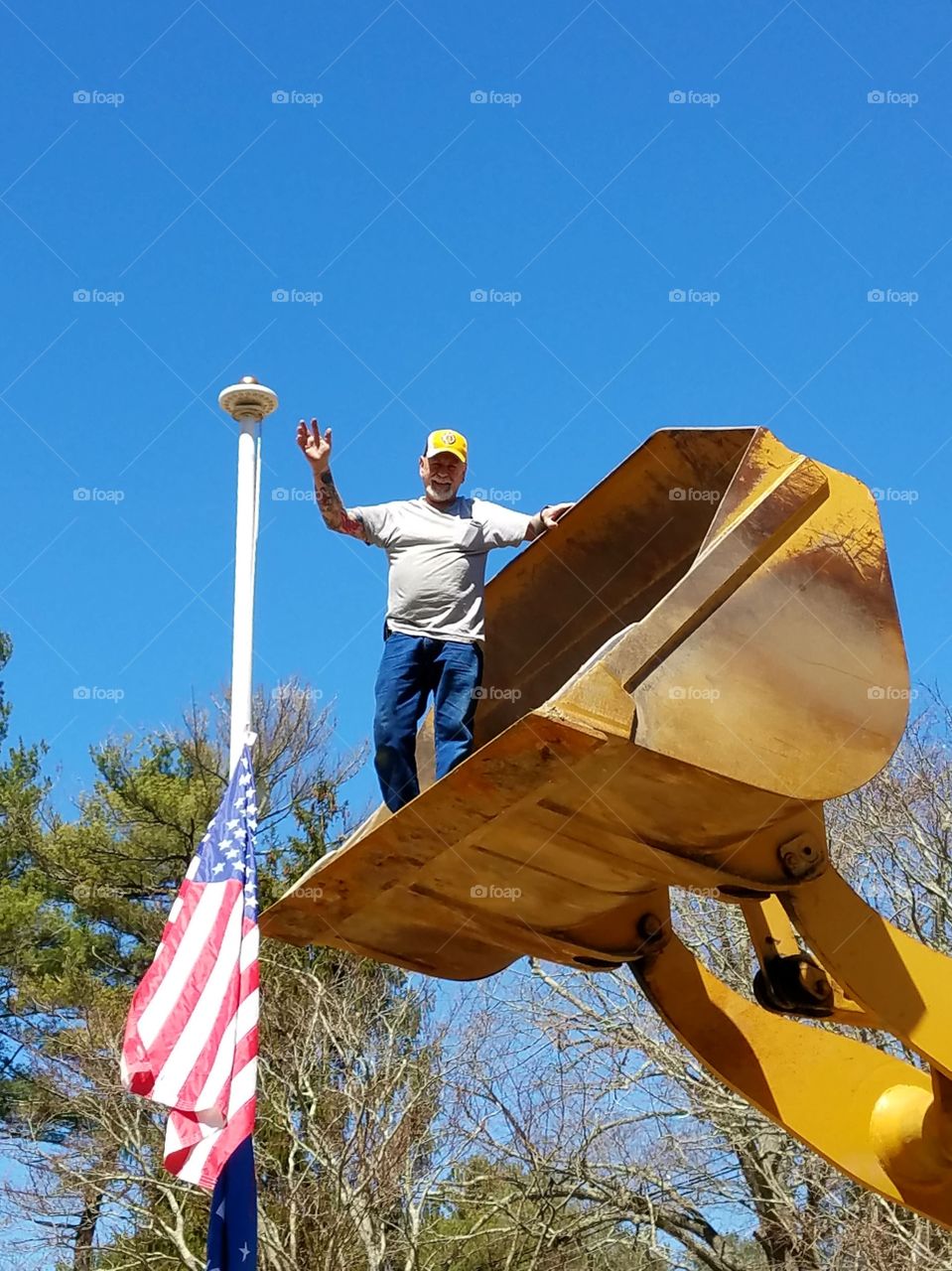 Solar Light installed by laborer on flagpole top using Bucket Loader Bucket all the way up, up! Flag lowered on mast to do job.